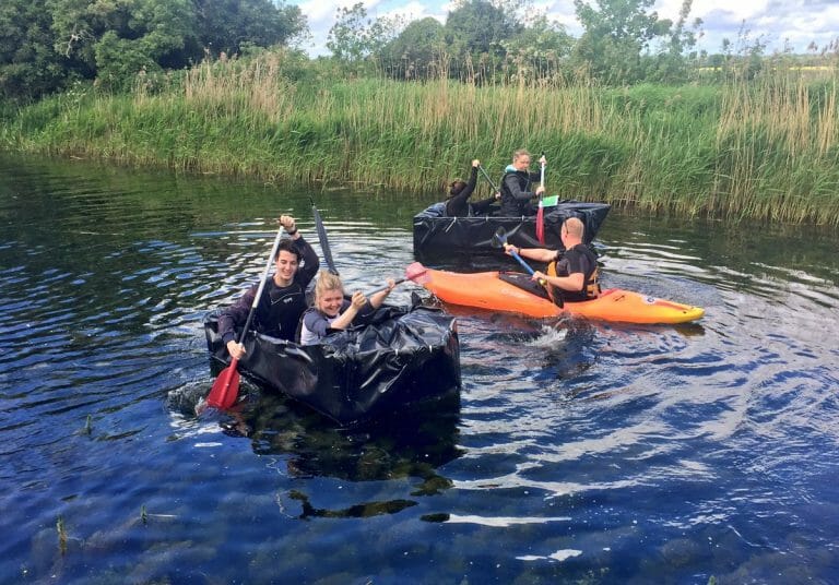 Delegates rowing down the river in a cardboard boat he built during his team-building activity with Orangeworks.