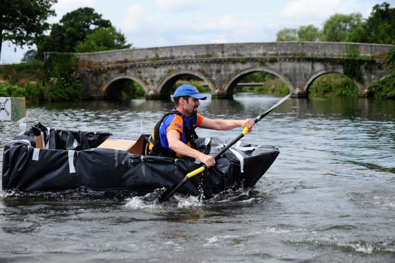 Delegate rowing down the river in a cardboard boat he built during his team-building activity with Orangeworks.