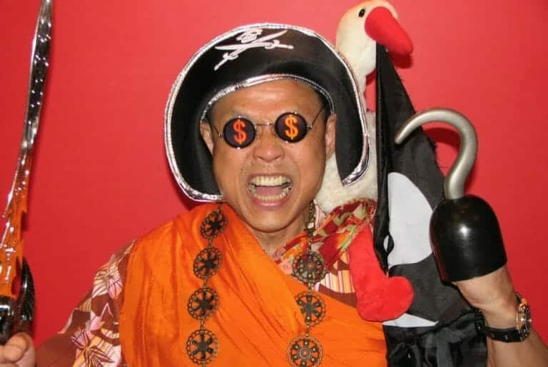 A man posing as a pirate for the team engagement event by Orangeworks. He has a hat and parrot on his shoulder and is holding a hook and a sword.