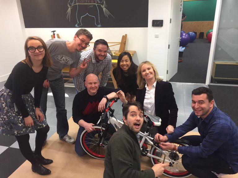 Charity Bike Build- Corporate Social Team smiling with their newly built bike for charity during Orangeworks team building activity Charity Bike Build.