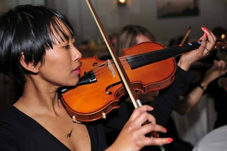 Delegate learning how to play the violin during a music-themed team building activity, Crescendo, with Orangeworks.