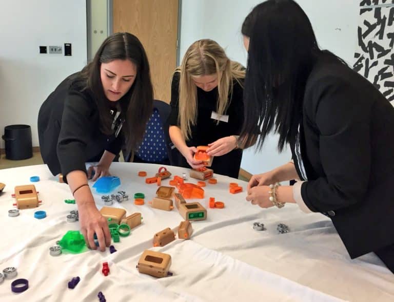 Delegates work together to build model cars during Orangeworks team building game called need for speed.