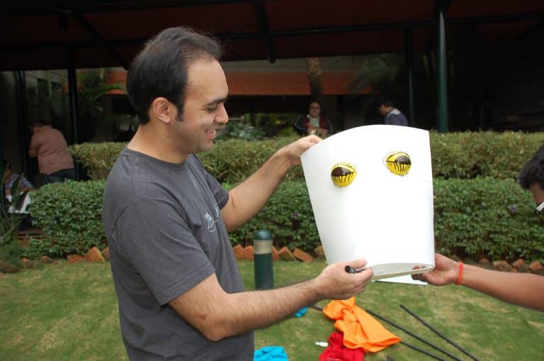 A man holding up the head part of the puppet he is creating with his team during the team building activity with Orangeworks.