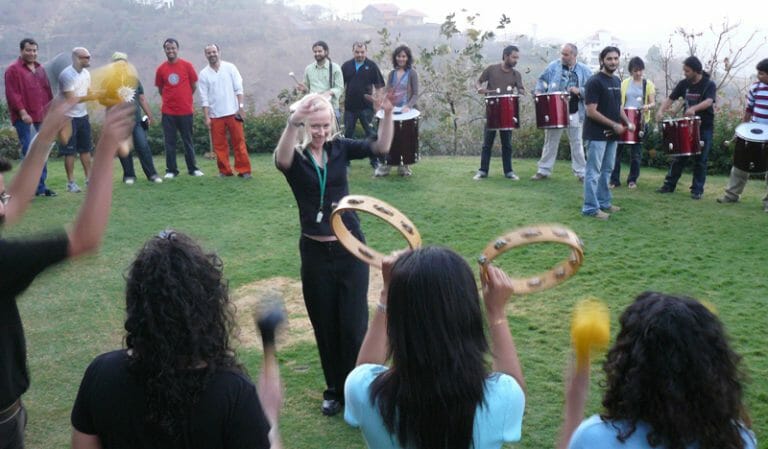 Delegates stand around in a circle outside ready rot play their Revel Music instruments with Orangeworks.
