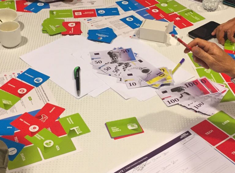 Global Innovation Game money and playing cards scattered on table
