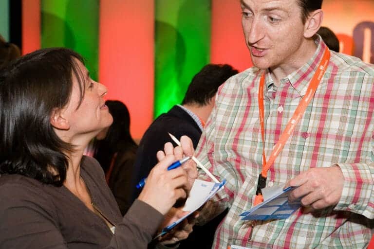 Delegates having a discussion regarding their common interests and writing them down on the questions card during Orangeworks team bonding event