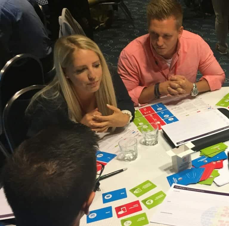 Delegates sitting around a table discussing their product idea for Global Innovation Game, a fun team building challenge.