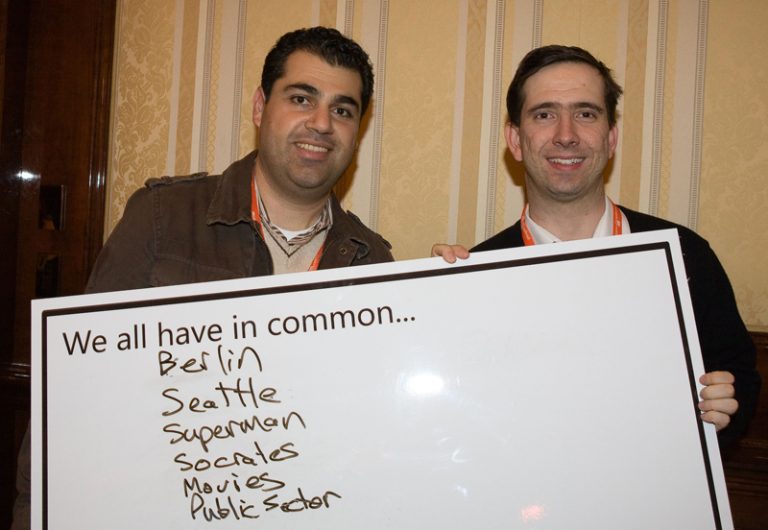 Participants holding up a whiteboard with things they have in common during Knowing Me Knowing You, an icebreaker activity by Orangeworks.