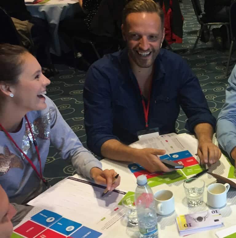 Delegates sitting around a table discussing their product idea for Global Innovation Game, a fun team building challenge.
