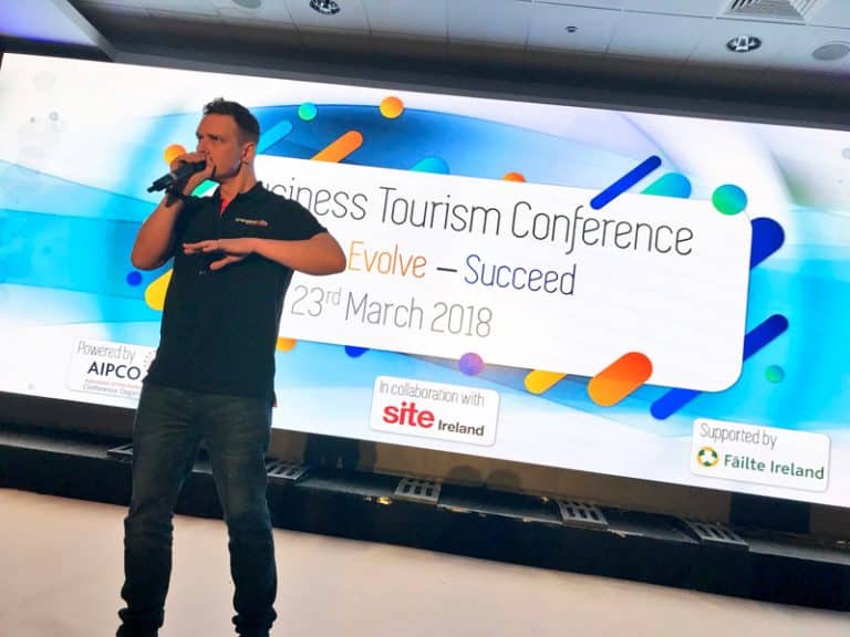 Dean, Orangeworks beatbox instructor, standing on stage at a Business Tourism Conference, teaching the participants how to beatbox.