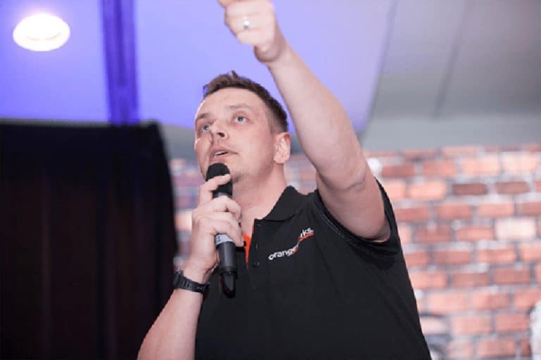 Orangeworks Beatboxer Dean, with his hand in the air, teaching the crowd at a corporate event how to beatbox.