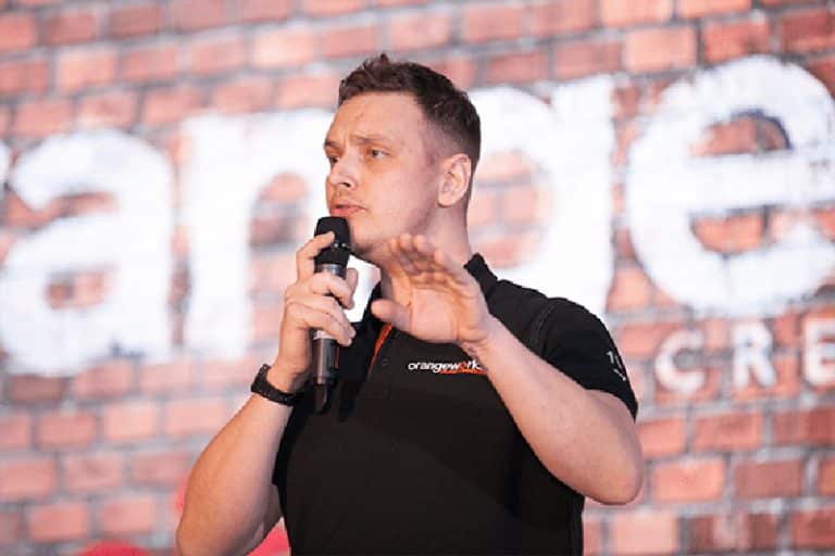 Dean, an Orangeworks Beatboxer, standing on stage at a team-building event teaching participants how to beatbox.