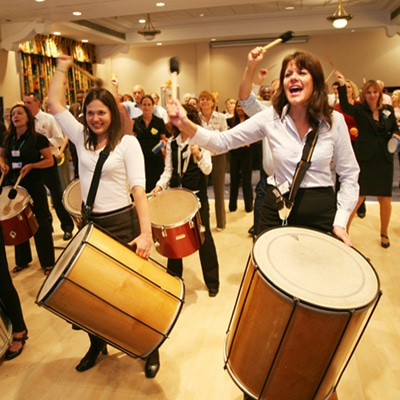 Delegates playing the drums during the Beatswork finale, a samba drumming team bonding experience with Orangeworks.