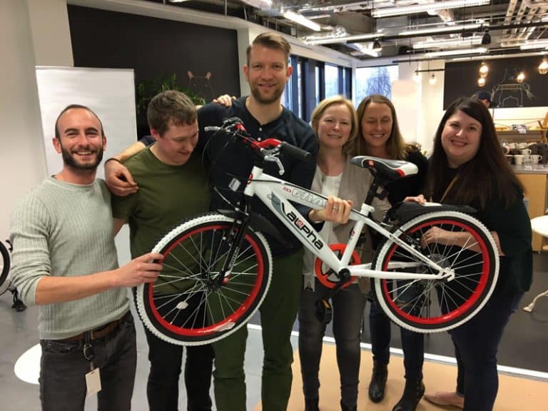 Team smiling with their newly built bike during Charity Bike Build, a charity themed corporate event.