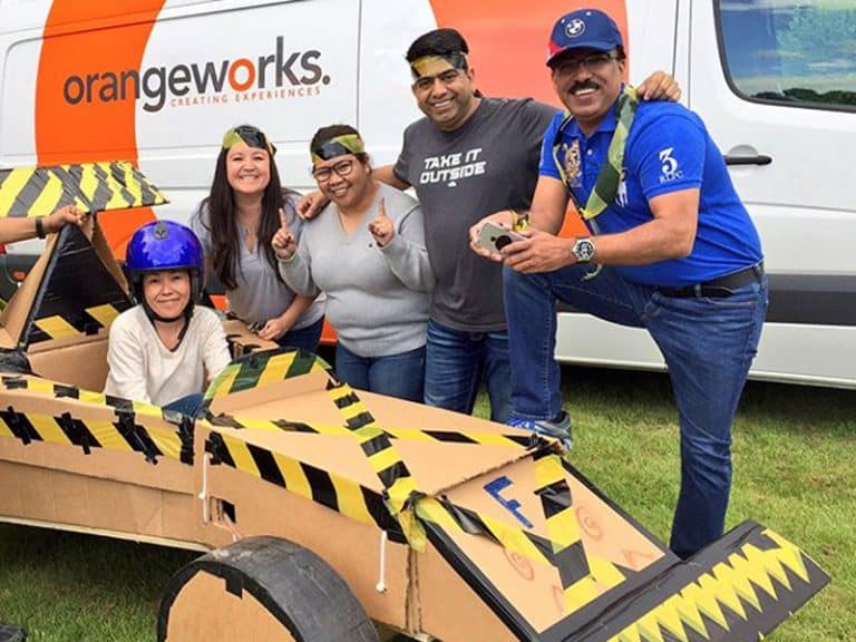 Delegates smiling with the cardboard formula one car they built during their fun team building experience.