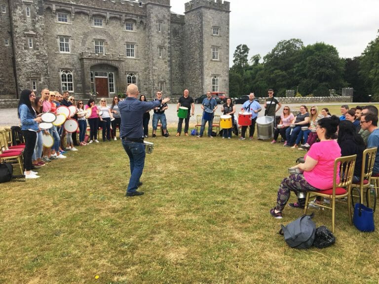 Participants sitting in a circle listening to the Beatswork instructor explain how the samba drumming workshop goes.