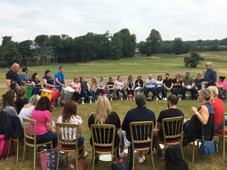 Delegates sitting outside Slane Castle in a circle ready for Beatswork, their team building challenge.