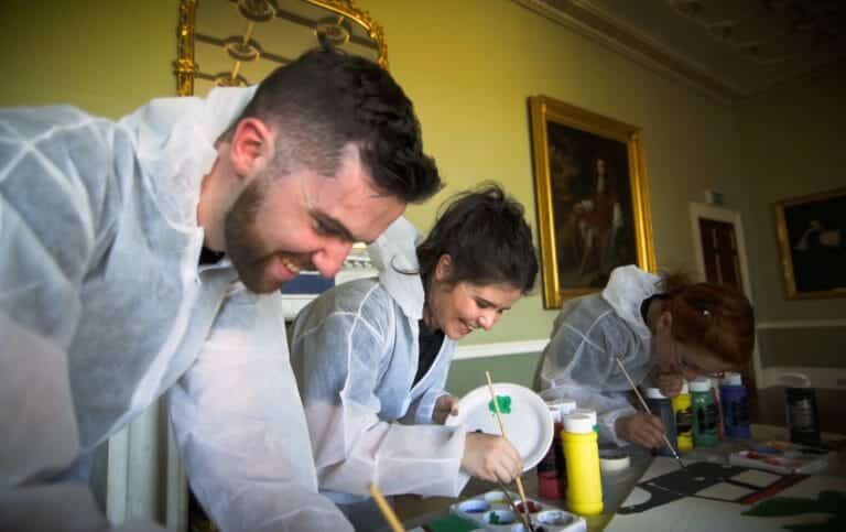 Delegates wearing white overalls painting canvases, during the fun, creative, corporate team building activity, Big Picture.