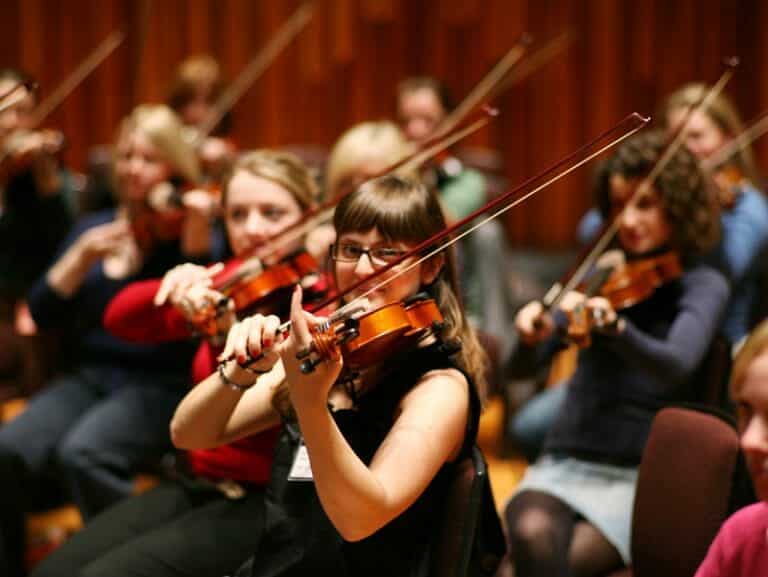 Participants of the team bonding activity, Orchestrate learning to play the violin.