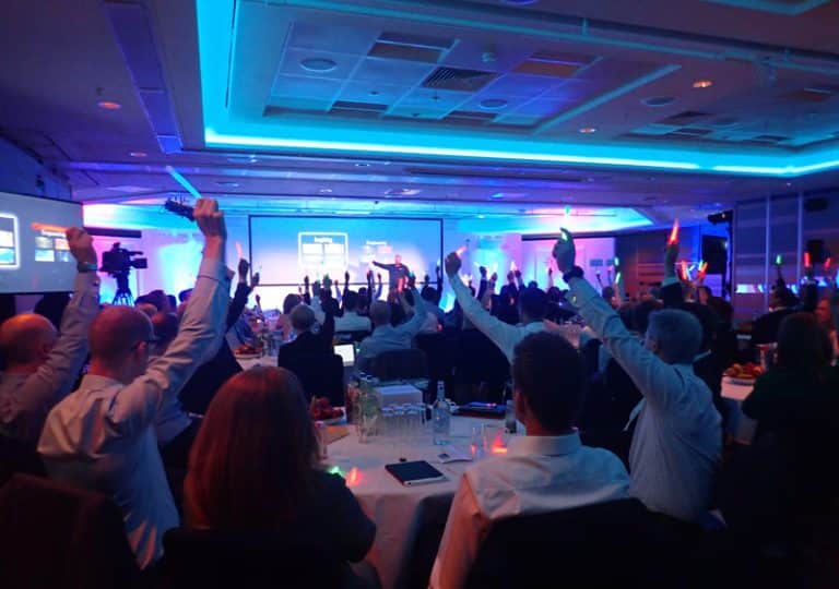 Delegates sitting at a conference holding light-up batons during Meditainment, a corporate wellness programme by Orangeworks