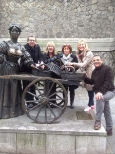 A group of people posing with the Molly Malone statue in Dublin's O Connell Street, during Orangeworks team building treasure hunt called Go Team Dublin.