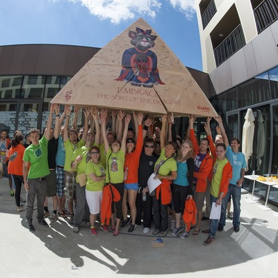 A team holding up a giant cardboard pyramid they made together during a team building exercise called flat out pyramids.