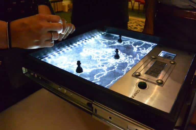 the red alert map game in a metal box with lights going through it, and a delegates hands on it.