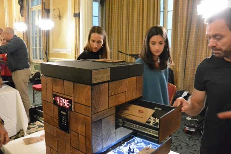 Two delegates playing Red Alert. They are walking around a locked chest. A drawer is open and there is a code on the chest.