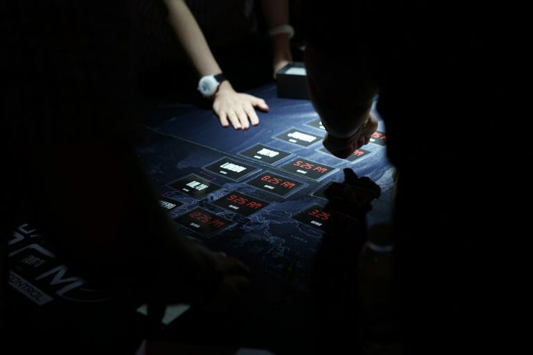 situation room with cards on the table. one lot of cards has times and the other has words. very darkened photo.