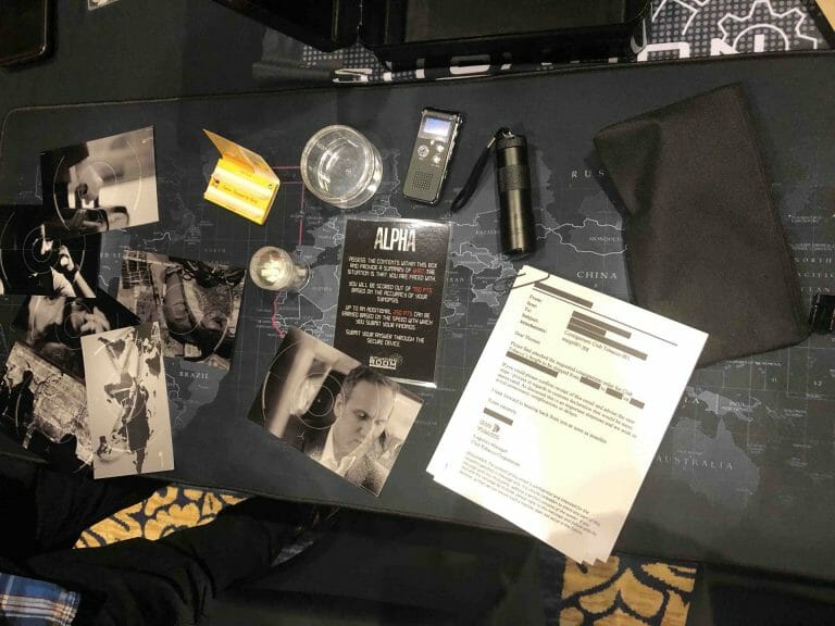 situation room with equipment out on the table, including photos, a torch, a bag, jars and paper documents.