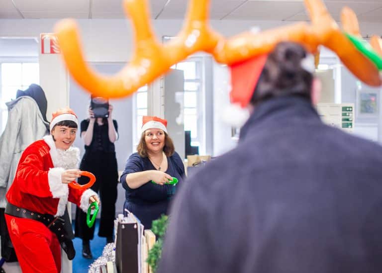 Delegates throwing inflatable rings onto an antler hat that another delegate is wearing during their Christmas themed team building activity with Orangeworks.