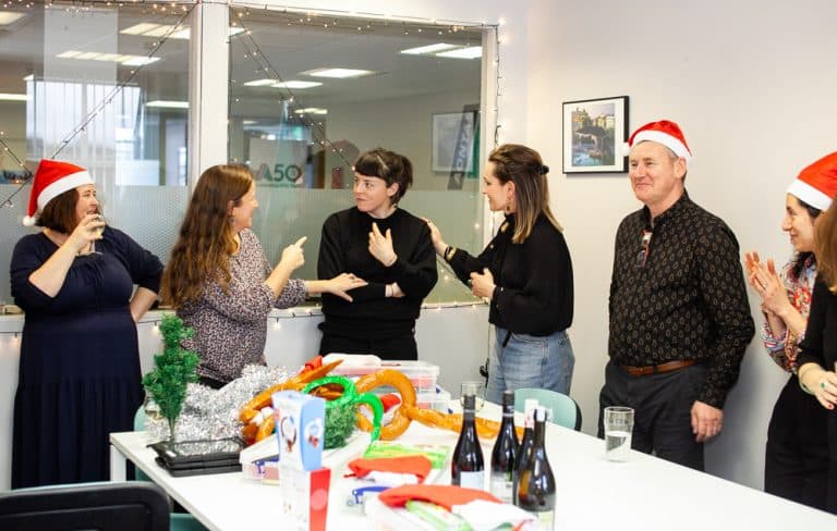 Delegates standing in a line chatting as they participate in Quickfire Christmas, a team building activity by Orangeworks.