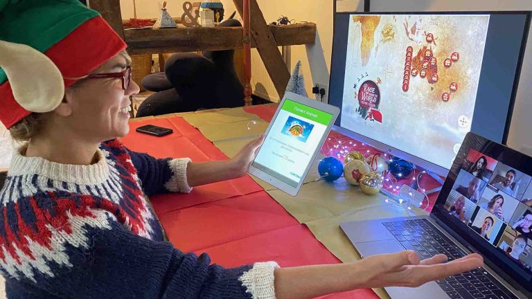 Delegate of Orangeworks remote team building activity Race Around the World Festive wearing a Santa hat and chatting with her team mates on Zoom.