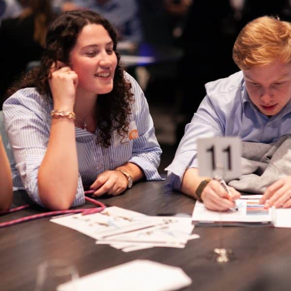 Delegates sitting at a table reading documents and instructions for Peak Performance, one of Orangeworks Team Development Activities.