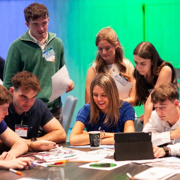 Delegates gathered around a table reading documents and instructions for Peak Performance, one of Orangeworks Team Development Activities.