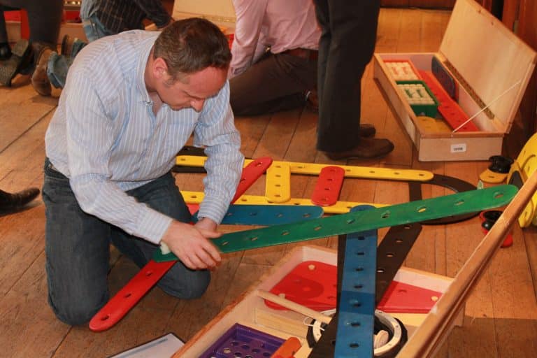 A delegate kneeling on the floor building his chain reaction contraption as part of a team building workshop with Orangeworks.