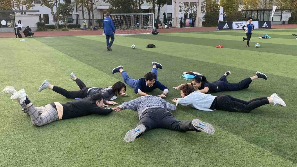 Delegates lying on the ground in a circle posing for a photo as part of their Quickfire Olympics team building challenge with Orangeworks.