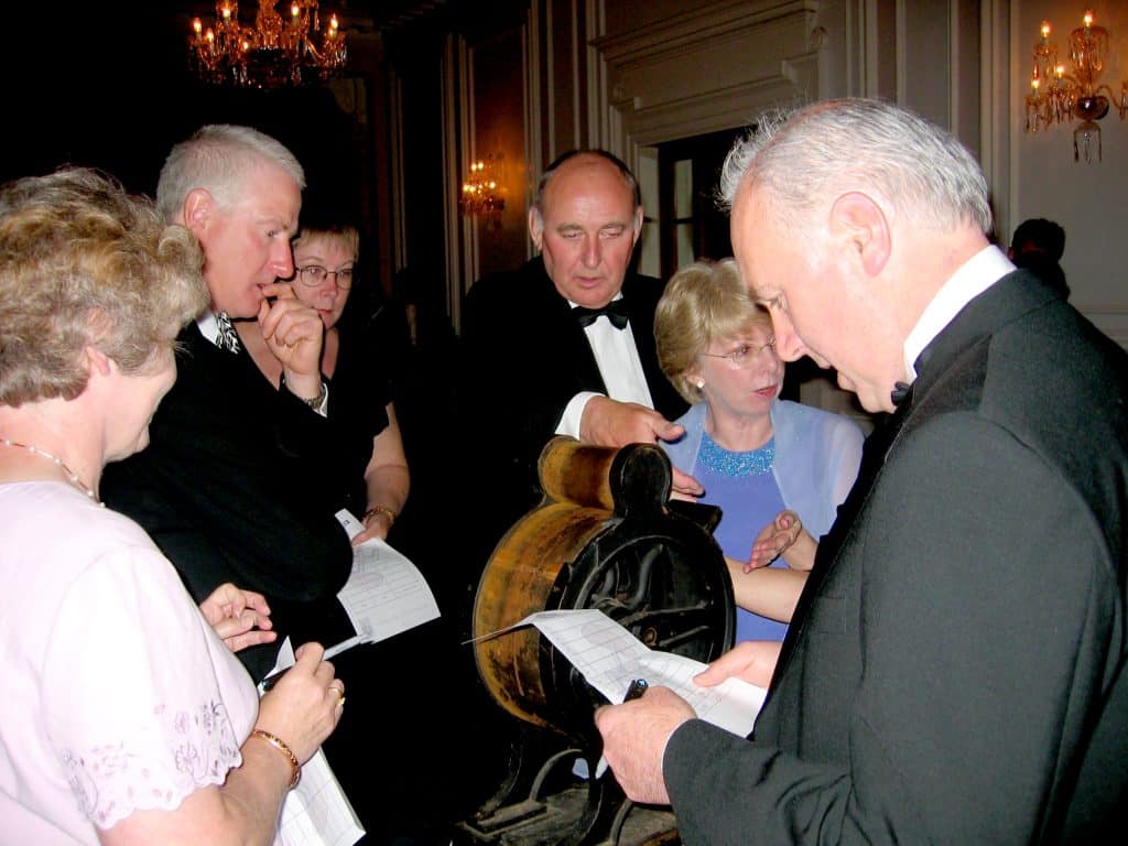Six delegates looking at and taking notes on one of the antiques used as part of Orangeworks team building activity called The Curio Show.