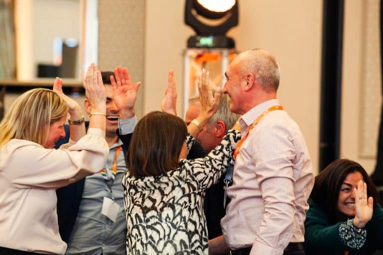 Delegates high fiving after completing the Green Game, CSR based team building challenge with Orangeworks.