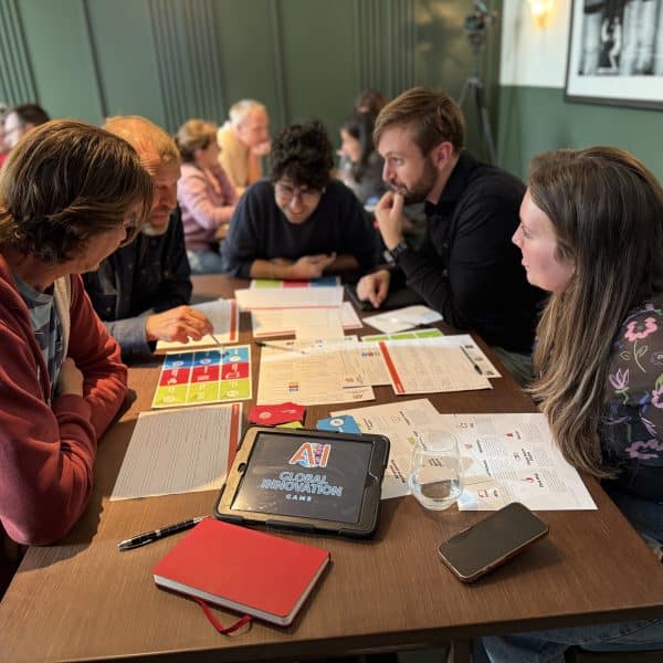 Delegates sitting around a table working on Global Innovation Game together - one of Orangeworks team development activities.