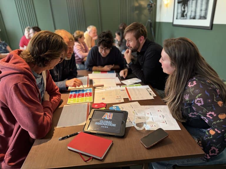 Delegates sitting around a table working on Global Innovation Game together - one of Orangeworks team development activities.
