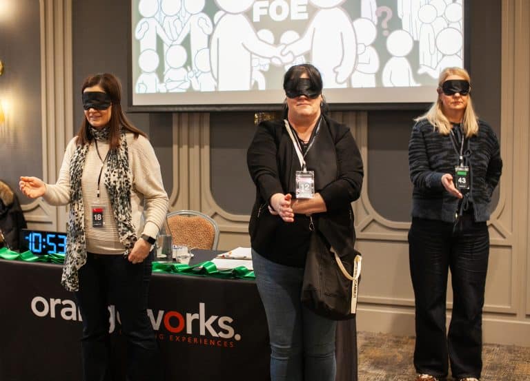 Delegates of Orangeworks team activity 'Friend or Foe', standing with blindfolds on waiting for our MC to shake their hand as part of the game.