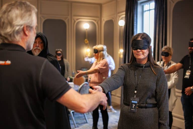 Delegates of Orangeworks team activity 'Friend or Foe', standing with blindfolds on waiting for our MC to shake their hand as part of the game.