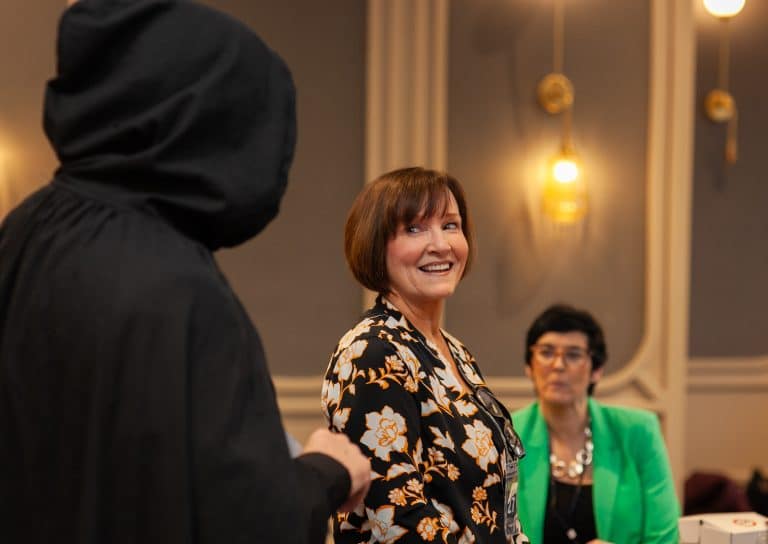 A delegate smiling while talking to our hooded MC, during Orangeworks Traitors inspired activity called Friend or Foe.