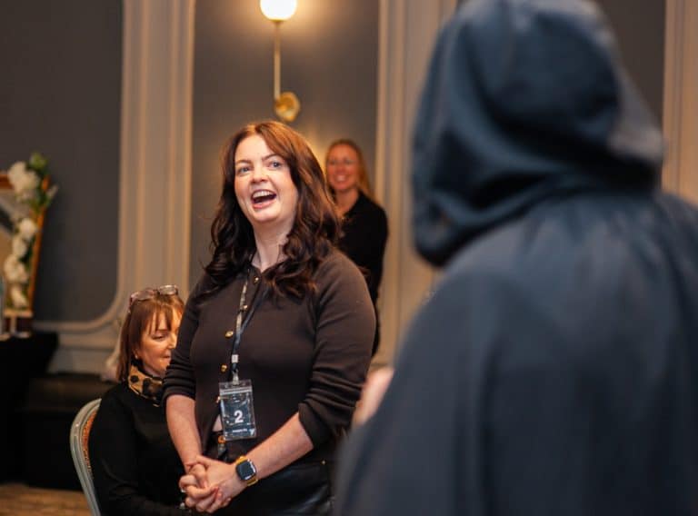 A delegate laughing while talking to our hooded MC, during Orangeworks Traitors inspired activity called Friend or Foe.