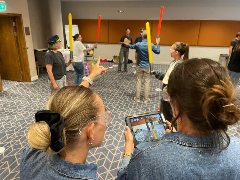 Delegates participating in one of Orangeworks fun team development activities called Drone Control. The aim of the activity is to successfully fly drones through man-made obstacles.