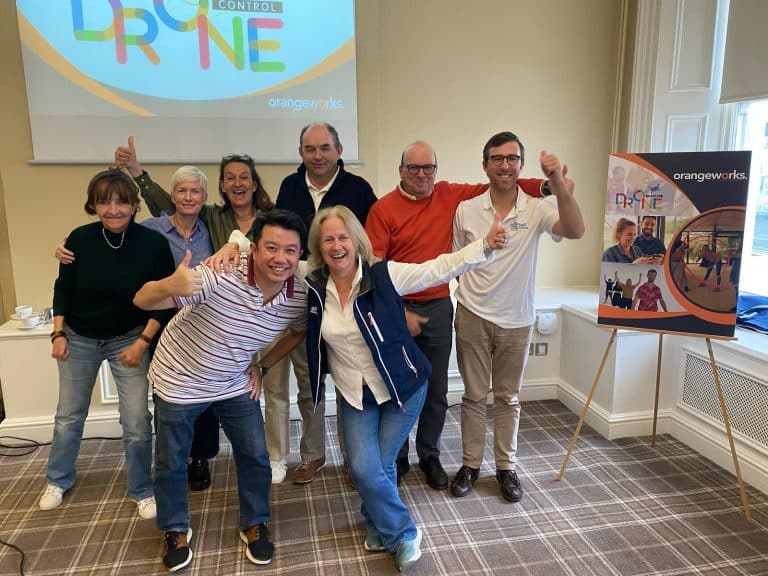 Delegates participating in one of Orangeworks fun team development activities called Drone Control. The aim of the activity is to successfully fly drones through man-made obstacles.