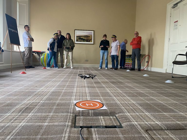 Delegates participating in one of Orangeworks fun team development activities called Drone Control. The aim of the activity is to successfully fly drones through man-made obstacles.